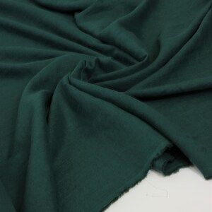 May include: A deep green fabric with a soft, textured surface. The fabric is folded and draped, showing its natural drape and texture.