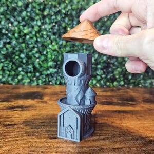 May include: A grey 3D printed tower with a brown roof. The tower has a round opening at the top and a small turret on the side. The roof is removable.
