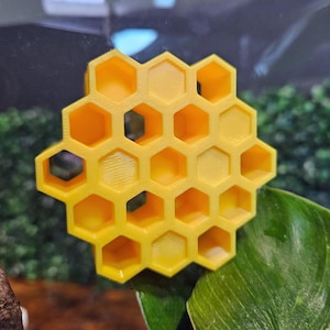 May include: A yellow honeycomb-shaped object made of plastic. The object is made up of multiple hexagonal cells.