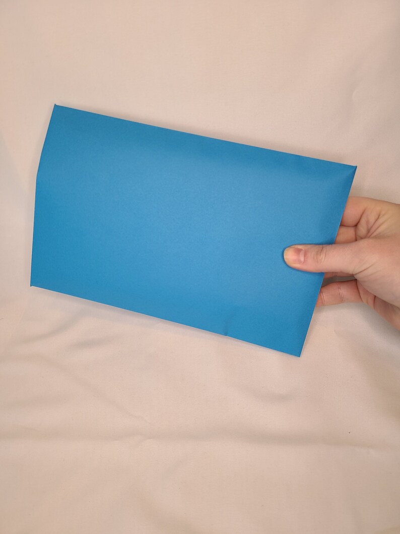 May include: A bright blue envelope, held in a hand, against a white background.