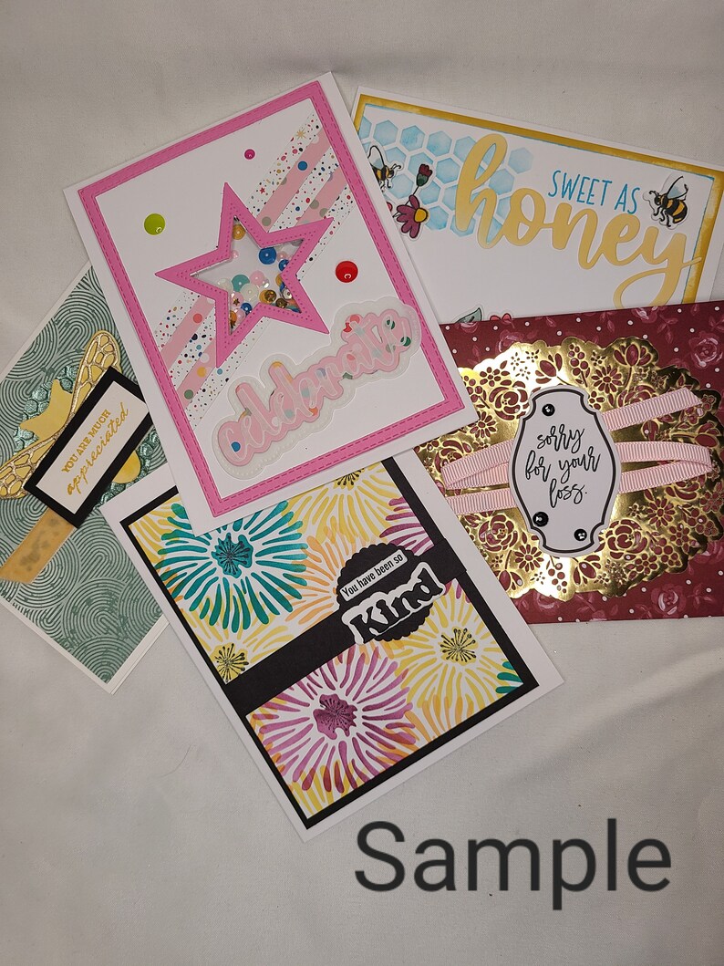 May include: A collection of handmade greeting cards with various designs and messages. The cards feature a pink card with a star and the word "celebrate", a green card with a floral pattern and the words "You are much appreciated", a yellow card with a floral pattern and the words "You have been so Kind", a honey-themed card with the words "Sweet as honey", and a burgundy card with a gold frame and the words "sorry for your loss".