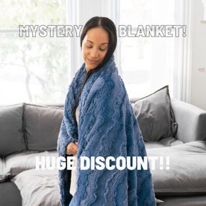 May include: A woman wearing a blue fuzzy blanket with the text "MYSTERY BLANKET! HUGE DISCOUNT!!" on the image.