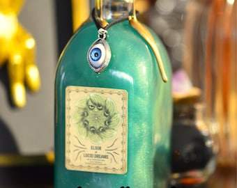 Könnte beinhalten: Eine grüne Glasflasche mit goldenem Verschluss und einem silbernen Augenanhänger. Die Flasche ist mit einer grünen Flüssigkeit gefüllt und trägt ein Etikett mit der Aufschrift "Elixir of Lucid Dreams".