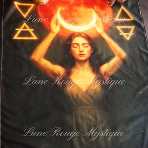 May include: A dark tapestry featuring a woman with closed eyes, holding a crescent moon above her head. A large red sun is behind her. The text "Lune Rouge Mystique" is written on the tapestry. Geometric symbols are in the corners.