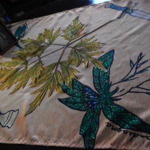 May include: A beige fabric tapestry with a green, blue, and black floral design. The tapestry features a sword, a candle, and the text "grace in the midst of chaos".
