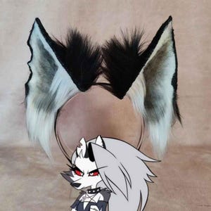 May include: A pair of black, white, and gray faux fur wolf ears attached to a headband. The ears are detailed with black tips and a fluffy texture. A cartoon wolf character with gray fur and red eyes is in the foreground.
