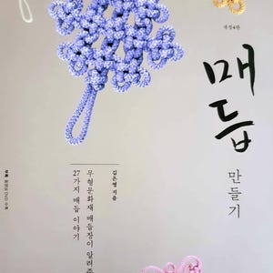 May include: A book cover featuring three decorative knotted cord ornaments in light purple, yellow, and white. The Korean text includes the title "매듭 만들기" and additional descriptive text about traditional knot-making techniques.