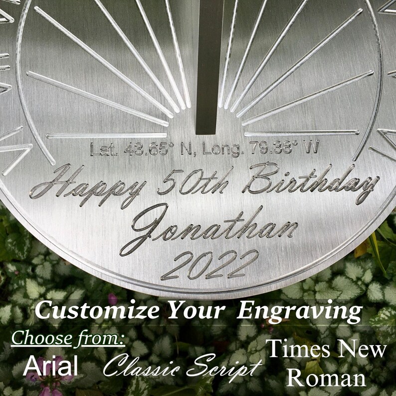 May include: A silver-colored sundial with a personalized inscription that reads "Happy 50th Birthday Jonathan 2022". The sundial also includes the coordinates "Let. 43.65&deg; N, Long. 79.38&deg; W".