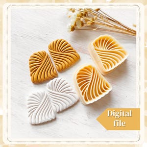 Puede incluir: Dos juegos de pendientes de arcilla polimérica en forma de corazón con un patrón ondulado. Un juego es blanco y el otro es dorado.