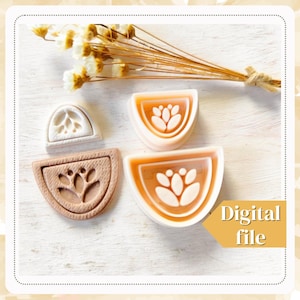 Pode incluir: Três moldes de silicone em forma de semicírculo com um design floral. Os moldes estão sobre uma superfície de madeira branca. Arquivo digital.