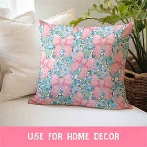 May include: A pink and blue throw pillow with a floral pattern featuring pink bows. The pillow is made of soft fabric and is perfect for adding a touch of color and style to any room.
