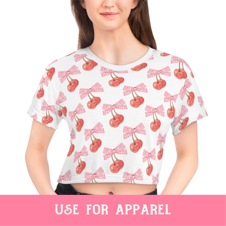 May include: White crop top with a pink and white cherry print. The cherries have pink bows.
