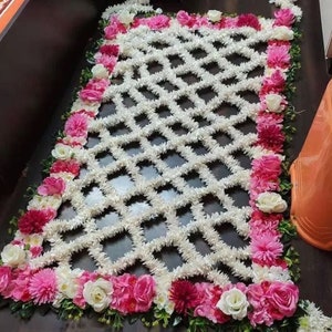 May include: A white floral design with a diamond pattern, surrounded by a border of pink and white flowers.