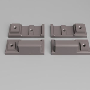 Puede incluir: Cuatro soportes metálicos grises con agujeros para montaje. Los soportes están dispuestos en forma de cuadrado.