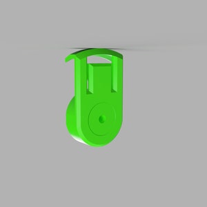 Può includere: Una puleggia di plastica verde brillante con un piccolo foro al centro. La puleggia ha una parte superiore curva e una parte inferiore arrotondata.