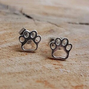 May include: A pair of silver paw print stud earrings. The earrings are small and delicate, and they would make a great gift for any dog lover.