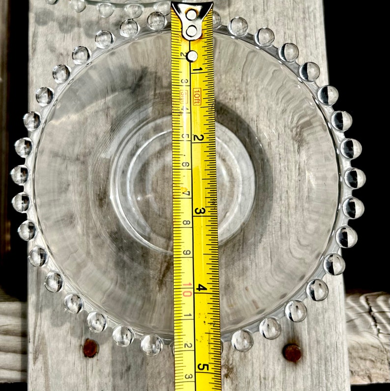 K&ouml;nnte beinhalten: Eine klare Glassch&uuml;ssel mit einem perlenbesetzten Rand, die einen Durchmesser von 10 cm hat. Die Sch&uuml;ssel steht auf einer Holzoberfl&auml;che.