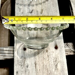 K&ouml;nnte beinhalten: Eine klare Glassch&uuml;ssel mit einem perlenbesetzten Rand. Die Sch&uuml;ssel hat einen Durchmesser von etwa 15 cm.