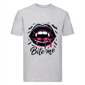 Puede incluir: Camiseta gris claro con un gráfico de labios negros con colmillos, goteando sangre roja y las palabras "Bite me". Pequeños murciélagos negros rodean los labios. El diseño está centrado en la camiseta.