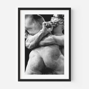 May include: Black and white framed print of a classical sculpture depicting two figures in a dynamic embrace. The sculpture is detailed, showing muscular forms and intricate textures. The artwork is set against a dark background.