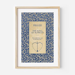 May include: A framed print of a book cover with a blue and gold floral pattern. The title of the book is "The Song of Achilles" by Madeline Miller. The quote "He is half of my soul, as the poets say." is printed below the title.