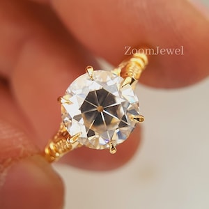 May include: A gold ring with a large, clear, round gemstone. The ring has a delicate, twisted band.