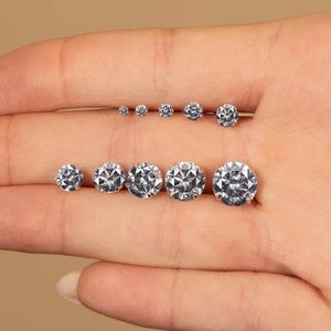 May include: A set of eight clear round gemstones of varying sizes, displayed on a hand.