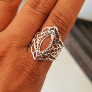 Può includere: Anello d'argento con un design delicato e intricato che presenta una grande montatura ovale. L'anello è mostrato su un dito.