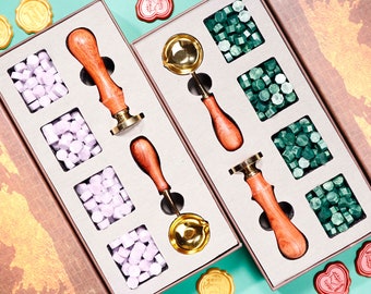 May include: Two decorative wax seal kits. Each kit includes a wooden handled stamp, wax beads, and a melting spoon. One kit has purple wax beads, the other has green. The stamps have brass seal heads.