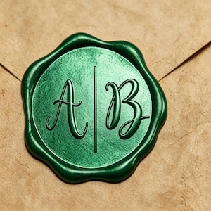 Puede incluir: Un sello de cera circular de color verde metálico con las letras A y B en relieve, separadas por una línea vertical. El sello presenta un borde irregular y ondulado, con una superficie lisa y reflectante sobre papel marrón texturizado.
