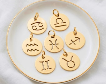 Puede incluir: Siete colgantes circulares de metal dorado, cada uno con un símbolo del zodiaco recortado. La colección incluye los signos de Cáncer, Libra, Acuario, Piscis, Sagitario, Géminis y Tauro, todos equipados con pequeñas anillas para colgar.