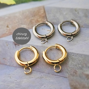 Könnte beinhalten: Vier Creolen-Ohrringe in Gold- und Silberfarben. Jeder Ohrring hat unten eine kleine Schlaufe. Der Text "chirurg. Edelstahl" befindet sich in einem grauen Kreis. Die Ohrringe sind aus Chirurgenstahl.
