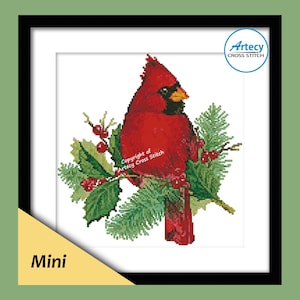 Könnte beinhalten: Gerahmtes Kreuzstichbild eines roten Kardinals, der auf einem Ast mit grünen Blättern und roten Beeren sitzt. Das Kunstwerk ist mit "Mini" beschriftet und enthält den Text "Artecy Cross Stitch".