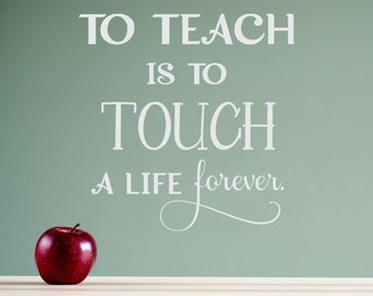 May include: A red apple sits on a white wooden surface in front of a green chalkboard with the quote "To teach is to touch a life forever." written in white.