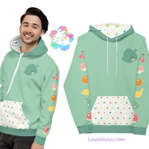 Puede incluir: Una sudadera con capucha verde con interior blanco y un bolsillo con un patrón de hojas y frutas coloridas. La sudadera tiene un diseño de hoja verde en la parte delantera y una fila de frutas y hojas en cada manga. El texto "Lovelibunni.com" está impreso en la parte inferior de la sudadera.