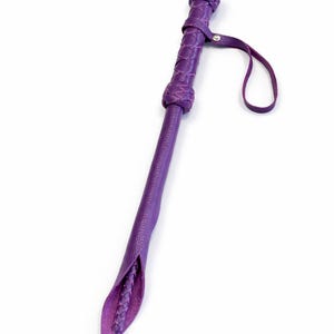 Puede incluir: Un l&aacute;tigo de cuero morado con un mango trenzado y un lazo. El l&aacute;tigo tiene un extremo c&oacute;nico con un interior trenzado. El mango y la parte superior del l&aacute;tigo tambi&eacute;n est&aacute;n trenzados.