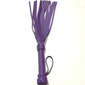 May include: A purple leather whip with a braided handle and a fringe of leather straps.