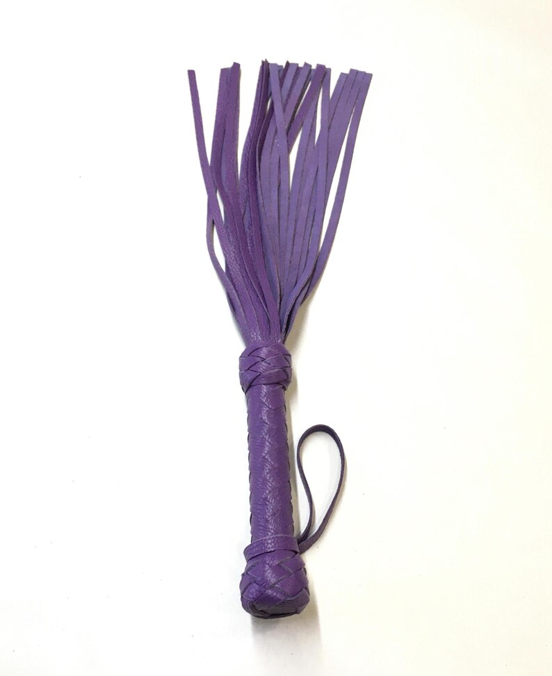 May include: A purple leather whip with a braided handle and a fringe of leather straps.
