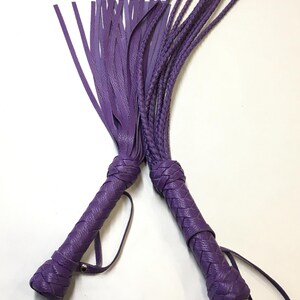 May include: Two purple leather whips with braided handles and fringe tassels.