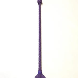 May include: A purple leather riding crop with a braided handle and a flat, rectangular paddle.