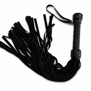 May include: A black leather flogger with a braided handle and a loop. The flogger features numerous long, thin, black leather falls. The handle is round and has a decorative knot at the base.