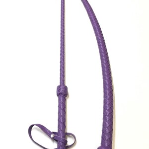 May include: Two purple leather whips with braided handles and straps. The whips are made of a soft, supple leather and have a classic design.