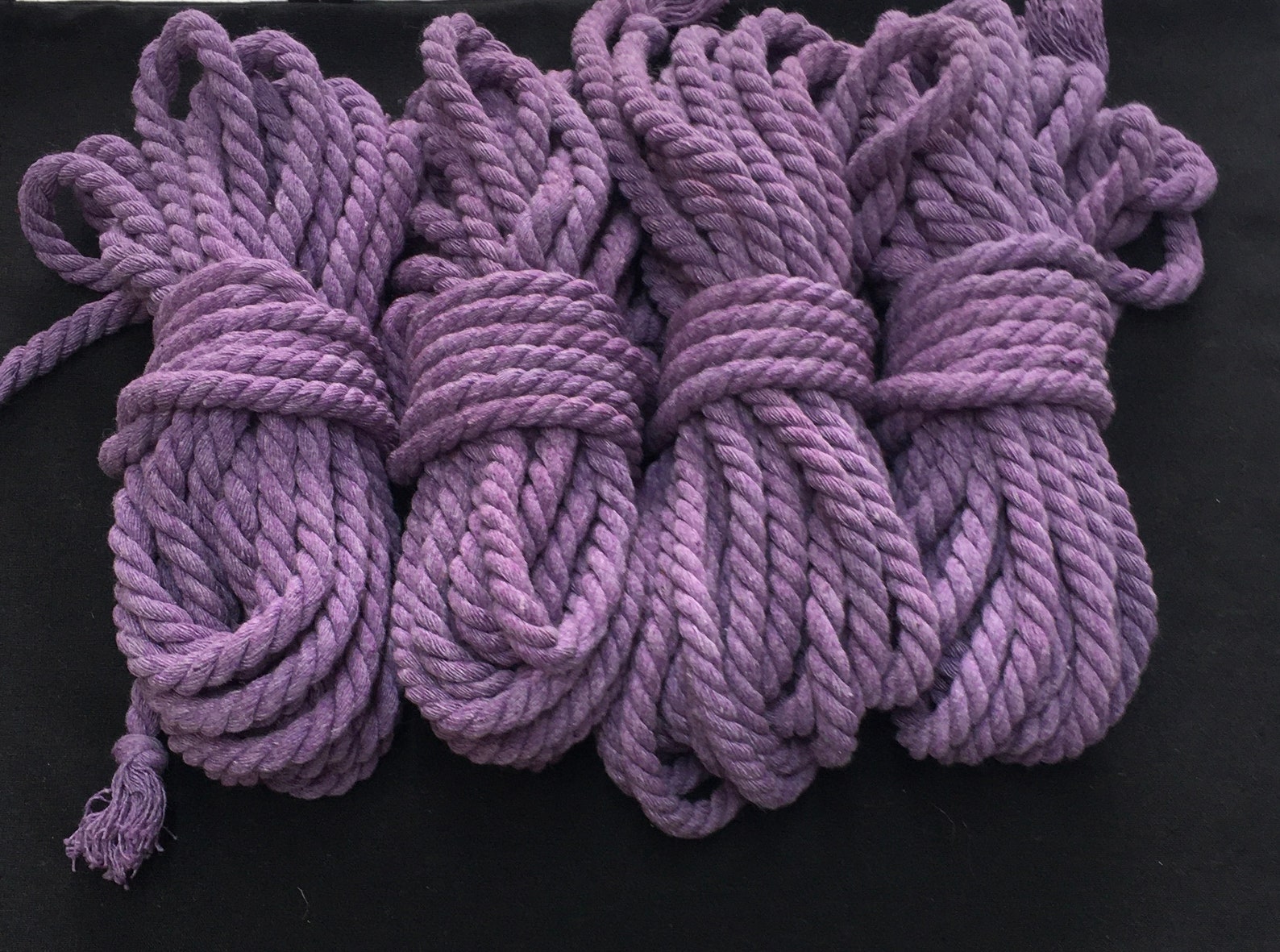 Purple cotton shibari ropes bundled together for bdsm ties, wrist restraints, and elaborate bondage restraint designs.