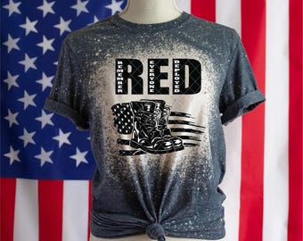 May include: A grey t-shirt with a bleached design featuring the words "RED" and "Remember Everyone Deployed" in white text. The design also includes a pair of black boots and an American flag.