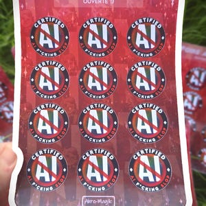 May include: A rectangular sticker sheet with a red background featuring twelve circular stickers. Each sticker displays a white letter A with a red slash through it, surrounded by the text Certified AI F*cking Slop. The sheet header reads FOIRE AU SLOP OUVERTE :) and includes the text Aure-Magik at the bottom.
