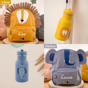 May include: Two personalized backpacks and water bottles. The backpacks are yellow with a lion face and gray with an elephant face. The water bottles are blue with an elephant face and yellow with a lion face. The backpacks and water bottles are labeled with the names "Leo" and "Lucas".