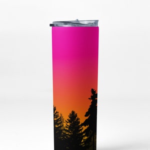 May include: A pink, orange, and yellow gradient stainless steel tumbler with a black silhouette of a forest at sunset.