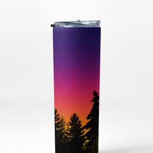 May include: A stainless steel tumbler with a purple to orange gradient design featuring a silhouette of a forest at sunset.