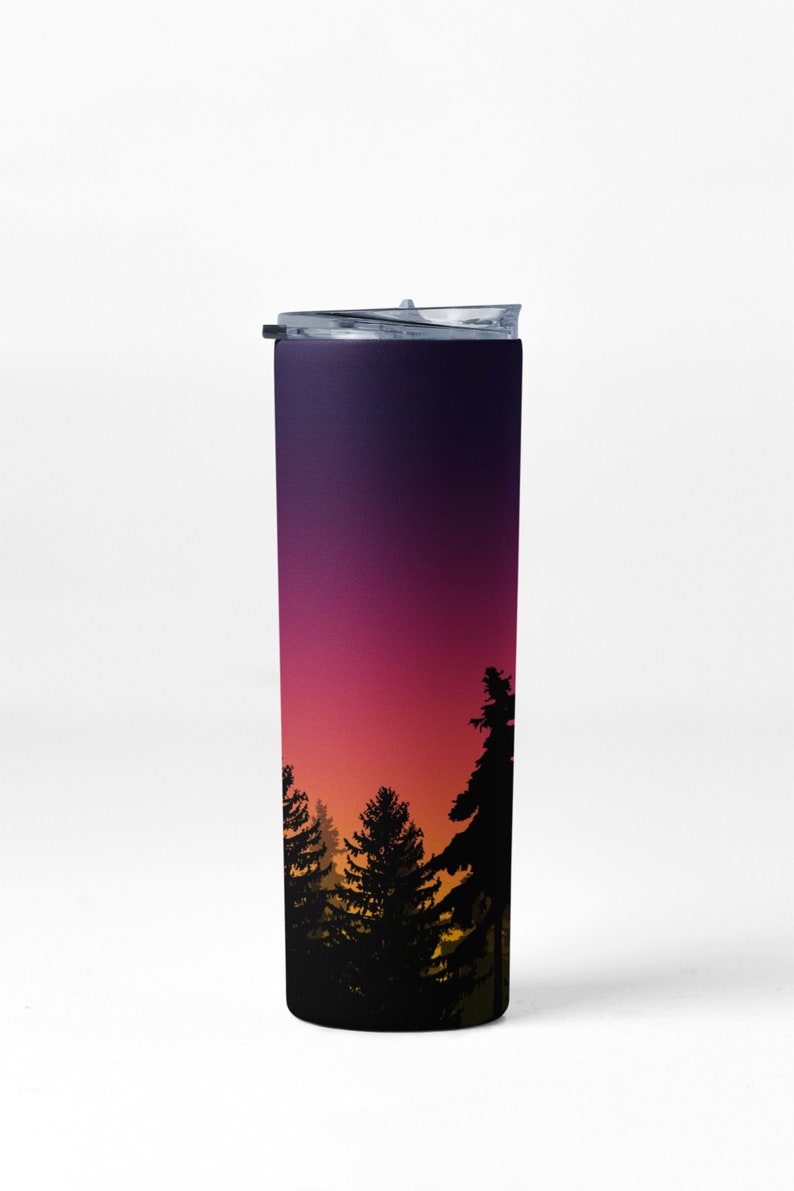 May include: A stainless steel tumbler with a black lid and a gradient design of purple, pink, orange, and yellow. The design features a silhouette of a forest at sunset.