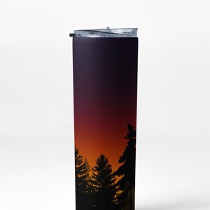 May include: A black and purple stainless steel tumbler with a clear lid. The tumbler features a sunset scene with silhouetted trees.